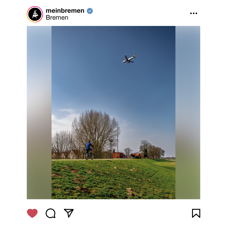 An einem Deich fährt ein Mann Fahrrad. Über ihm fliegt ein Flugzeug