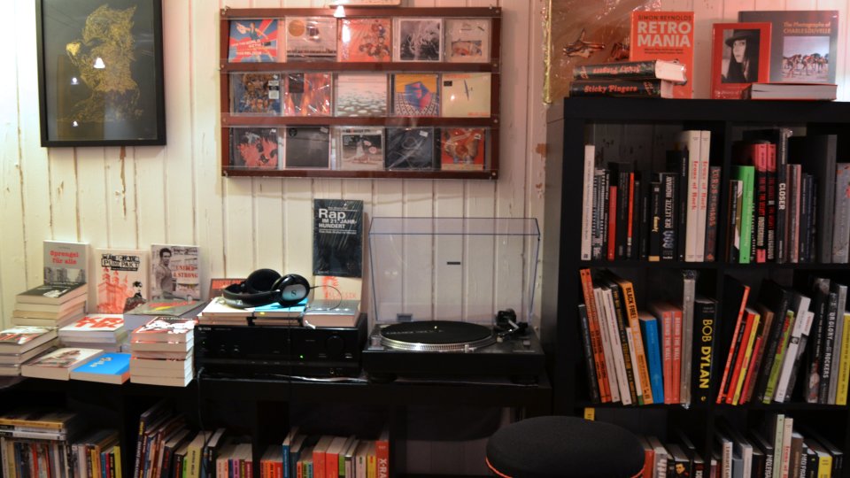 Ein Schallplattenspieler und Kopfhörer umgeben von Büchern und Schallplatten.