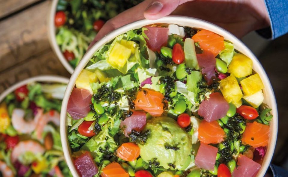 Eine Bowl gefüllt mit Salat, Bohnen, Lachs und Avocado. 