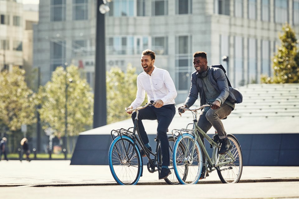Zwei Männer fahren mit ihrem Swapfiets Fahrrad zur Arbeit