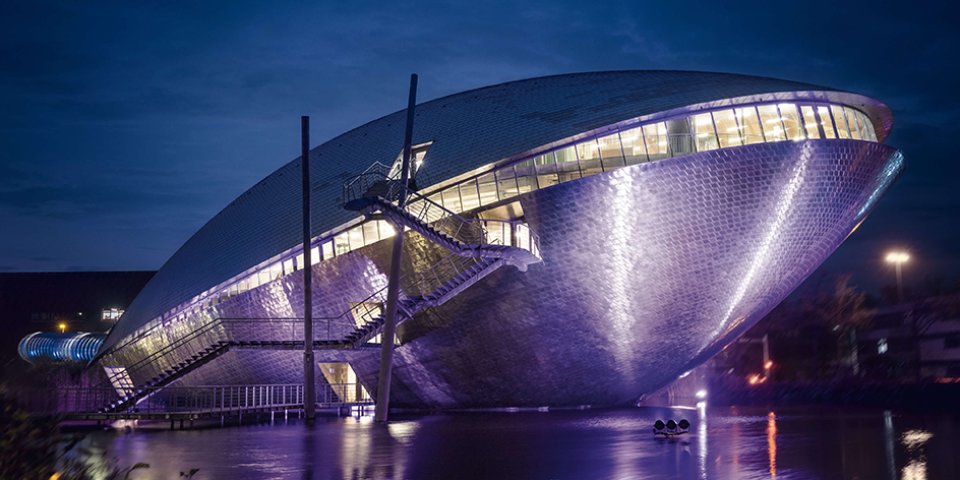 Die Außenansicht des Universum Bremen zeigt das Dauerausstellungsgebäude bei Nacht. Die Form des Gebäudes erinnert an eine Mischung aus Wal und Muschel.