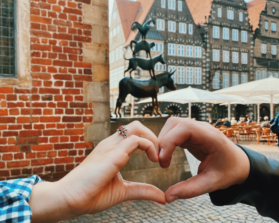 Zwei einander haltende Hände im Vordergrund, im Hintergrund die Stadtmusikanten