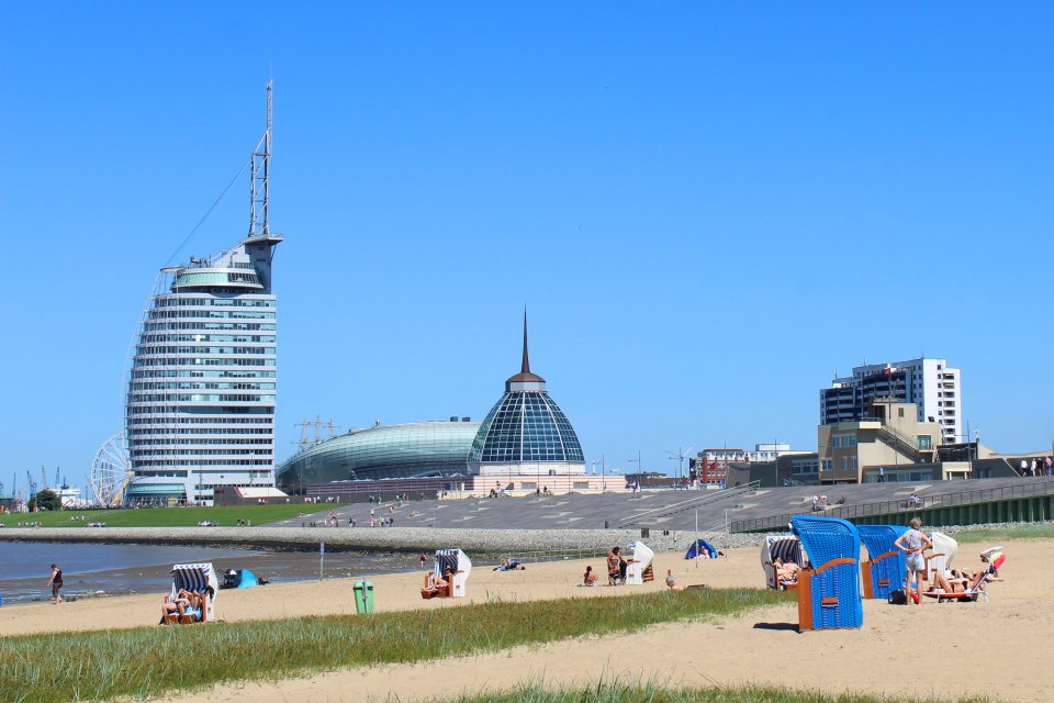 Strandkörbe am Sandstrand des Weser Strandbads. Im Hintergrund ist das Mediteraneo, das Klimahaus und das Sail City Hotel zu sehen.